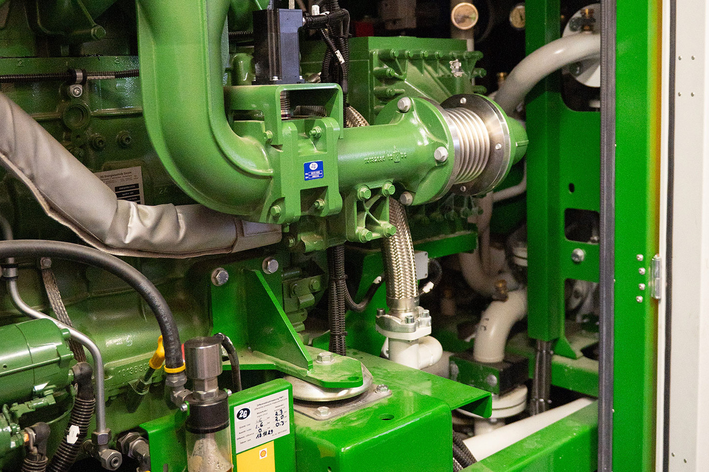 Close-up of a green machine module in a biogas digester with pipes, cables and technical components. The plant converts organic material into renewable energy.