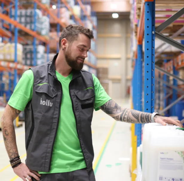 Ein Mann in einem grünen Tshirt schaut sich in einer Logistikzentrale um.